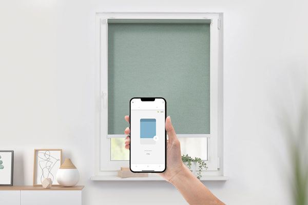 Rollos mit Smart-Home Funktion und Steuerung per Handy in grün angebracht in einem Fenster