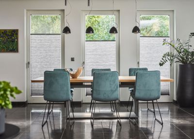 Blickdichte Plissees in Grau angebracht in bodentiefen Fenstern in einem Esszimmer