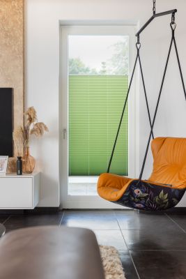 Lichtdurchlässige Plissee in Grün in einem bodentiefen Fenster im Wohnzimmer