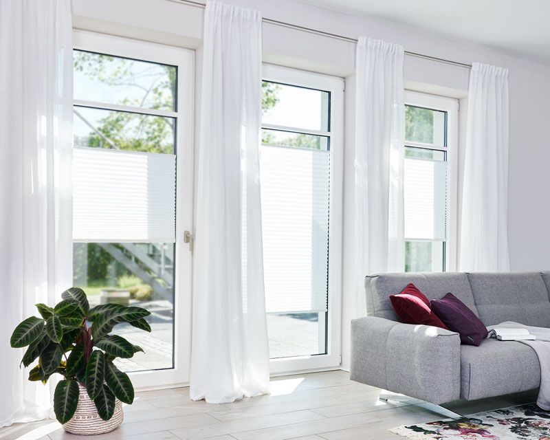 Plissees für alle Räume in einer Terrassentür in einem Wohnzimmer