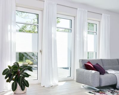 Lichtdurchlässige Plissee in Weiß angebracht in bodentiefen Fenstern in einem Wohnzimmer